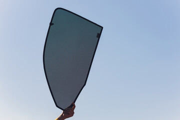 Hand holding folding sunshade retractable for windows or car windshield.