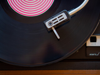 Detail of a needle on a track of a black vinyl record. Vintage turntable.