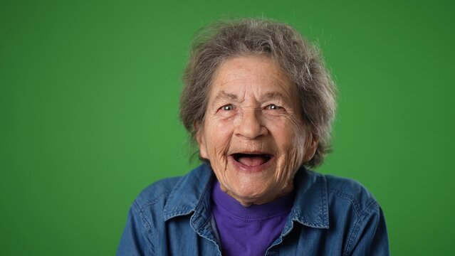 Closeup Portrait Of Toothless Elderly Senior Old Woman With Wrinkled Skin And Grey Hair Getting Great Happy With Success Winner Isolated On Green Screen Background. Emotions Concept