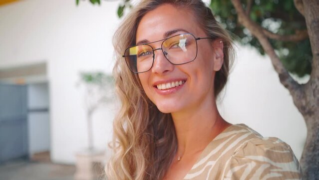 Face portrait of attractive girl in glasses. Beautiful and confident young business woman with glasses and long curly hair smiling looking at camera