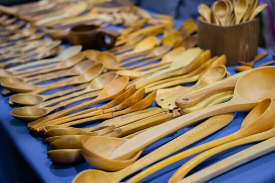 Handmade carved wooden spoons, kitchen utensils on counter of craft fair, trade show - close up. Handcraft, vintage, woodwork and carpentry concept