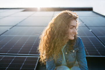 Portrait of young woman on roof with solar panels.