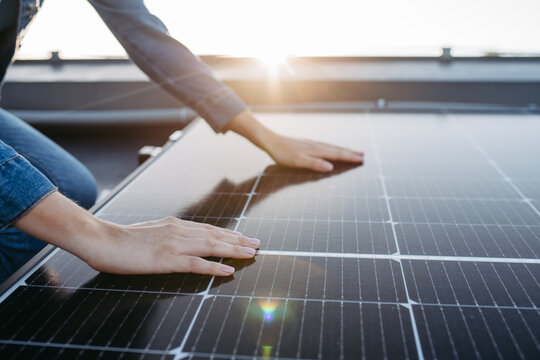 Close up of woman touching solar panels on the roof.