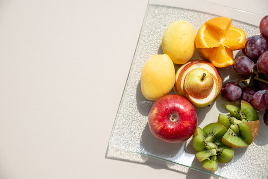 Raw fruits berries platter, oranges, kiwi , grapefruit, grapes, pear, apples on the plate, on the white table, top view, selective focus.Vegan. Healthy food,weight loss concept. copy space
