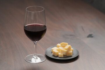 glass of red wine with vintage cheese on small plate
