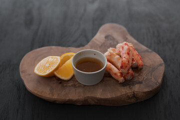 Crab served with sauce and sweet lemon on olive wood board
