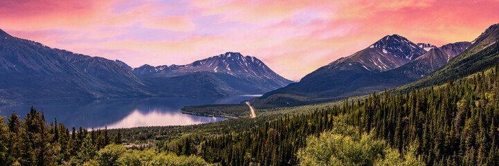 Panoramic pink sunset views over a wilderness area near Alaska during summer time with pastel pink...