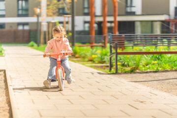 Little girl riding balance bike in the courtyard of the residence in Prague, Europe