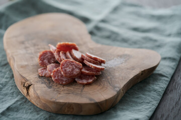 Sliced cured sausage on olive serving board