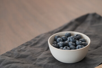 Fototapeta na wymiar Fresh washed blueberris in white bowl on linen cloth