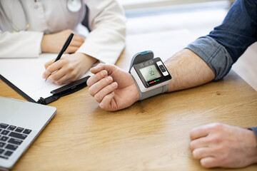 Crop of male patient measuring blood pressure with modern electronic tonometer in medical centre....