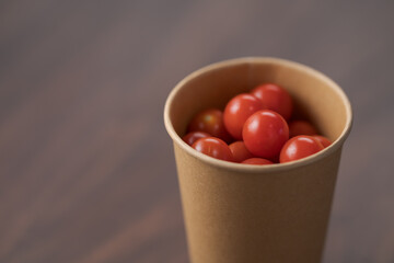 Cherry tomatoes in papaer cup container on wood table