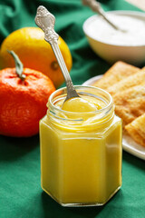 Kurd of lemons and tangerines, pancakes and sour cream on a green background. Rustic style.