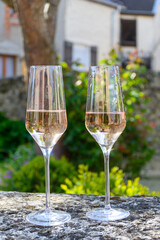 Tasting of premier cru sparkling rose wine with bubbles champagne with view on old houses of Hautvillers, where lived Benedictine monk how developed champagne wine, France.