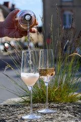 Pouring of premier cru sparkling rose wine with bubbles champagne with view on old houses of...