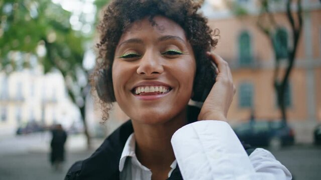 Positive girl listening song in earphones at street closeup. Lady enjoying music