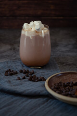 Hot chocolate in glass with marshmallows and chocolate and cookies on dark background 