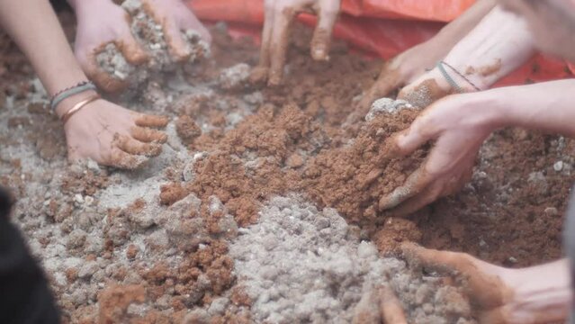 Low angle view of hands removing red construction sand with cement.