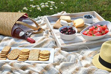 Romantic picnic with cheese, fruit and wine outside on a blanket in flower field. (Récolte on label means 