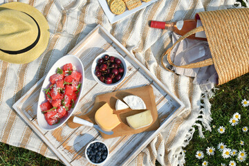 Romantic picnic with cheese, fruit and wine outside on a blanket in flower field. (Récolte on label means 