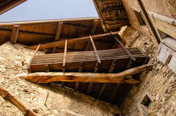 Detail of a wooden balcony built from natural materials in a historic building in Italy.