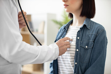 Cropped view of young brunette in denim jacket attending medical appointment at doctor's office in...