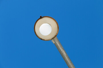 Public light seen from below with sky background.