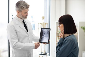Female brunette talking about discomfort under C collar while male physician explaining cause of...
