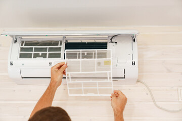 A man replaces and cleans the air cleaner filter from the air conditioner.