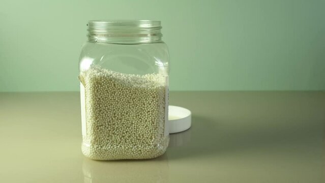 Tapioca pearls or white sago balls are poured with measuring spoon into glass bowl. Ingredient for Boba drink, Milk bubble tea or Tapioca pudding.