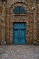 Large blue wooden doorway set into brick stone building.