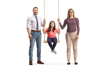 Fototapeta premium Mother and father standing next to girl on a wooden swing