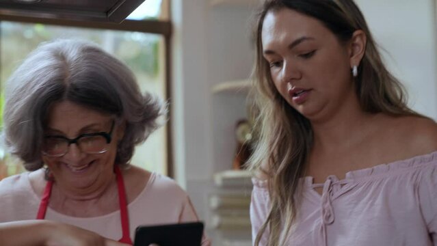 crian&ccedil;a brasileiro na cozinha ajudando sua m&atilde;e e av&oacute; a fazerem brigadeiro seguindo uma receita no tablet no dia das m&atilde;es