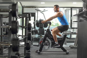 Plakat Man exercising cardio training in a gym on a stationary bicycle