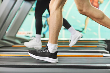 Male and female legs running on treadmills in gym