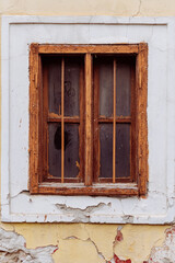 Old cracked wall with a window. window of old house. Old window with brown frame.