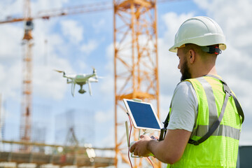 Drone operated by safety engineering inspector. Construction worker piloting drone on building site - 605041090