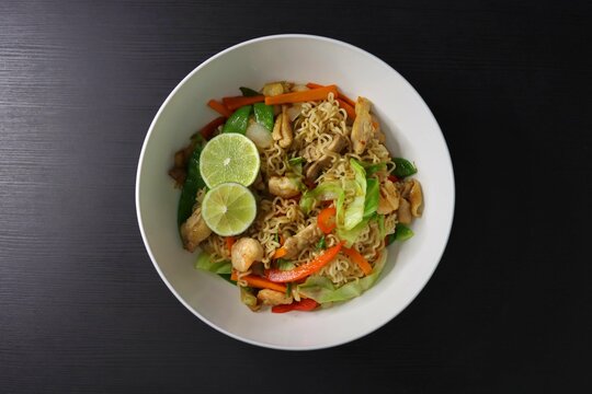 Pancit Canton Chow Mein Stir Fry Instant Noodles with Shrimp, Chicken, Cabbage, Carrots, Snow Peas, Red Peppers, Lime - Top Down View
