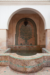 Moroccan indoor bath or pools with moorish arches, arabic tiles and architecture in the interior terrace of a riyad in Marrakech, Morocco.