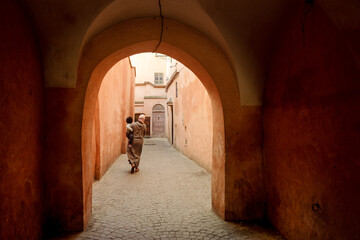 Obraz premium Woman walking with a baby through the moorish arches in the streets of the Marrakech Medina