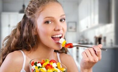 Happy young woman eat salad at home