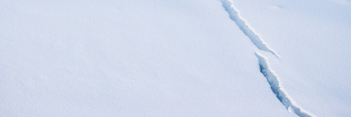 Crack in the ice cover. Snow covered ice. Cracked ice floes on the sea in the Arctic. Polar region. Snow texture. Wide panoramic texture for background and design.