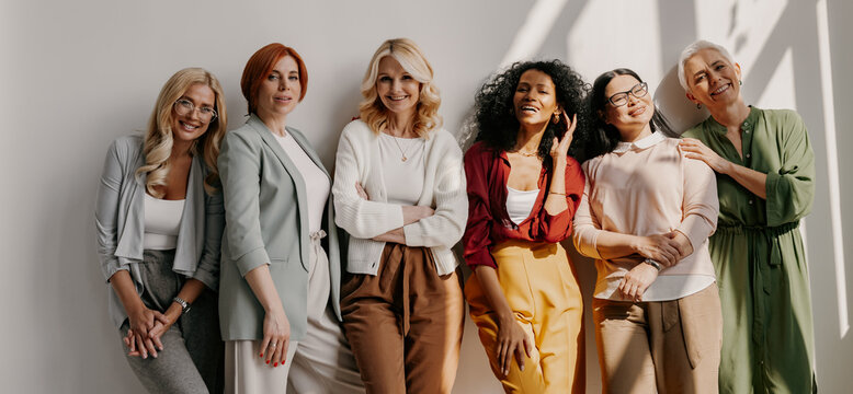Multi-ethnic group of relaxed mature women bonding and smiling while leaning on the wall