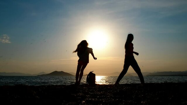 Children with a backpack. Silhouette of happy young girls running around the backpack on the beach.