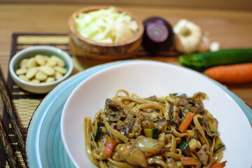 Rice noodles served with vegetables and meat in white bowl.