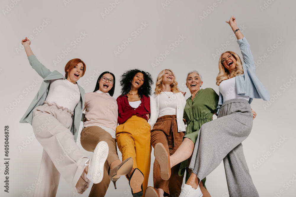 Wall mural Multi-ethnic group of cheerful mature women embracing and dancing against grey background