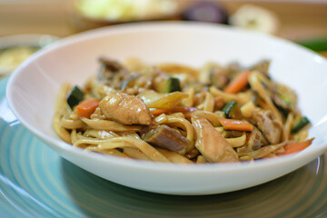 Rice noodles served with vegetables and meat in white bowl.