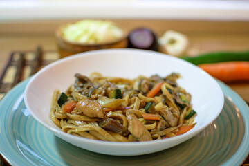 Rice noodles served with vegetables and meat in white bowl.