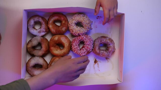 top view a whole box of delicious donuts is quickly taken by people's hands