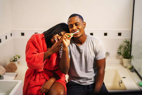 jovem casal brasileiro negro escovando os dentes juntos no banheiro sentados na banheira no dia dos namorados